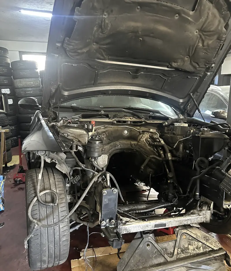 Frente de um carro desmontada na oficina, com o motor e a cablagem à vista
