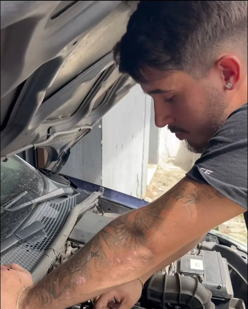 Mecânico da GT Auto Serviços debruçado sobre o motor de um carro, na oficina em Braga