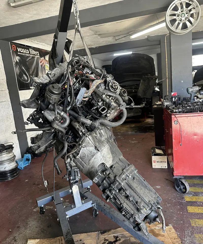 Motor retirado de um carro, suspenso numa grua da oficina