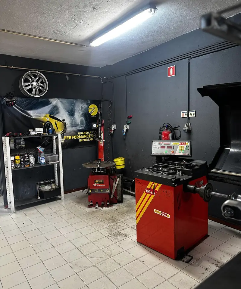 Interior da oficina com a máquina de equilibrar rodas e a desmontadora de pneus